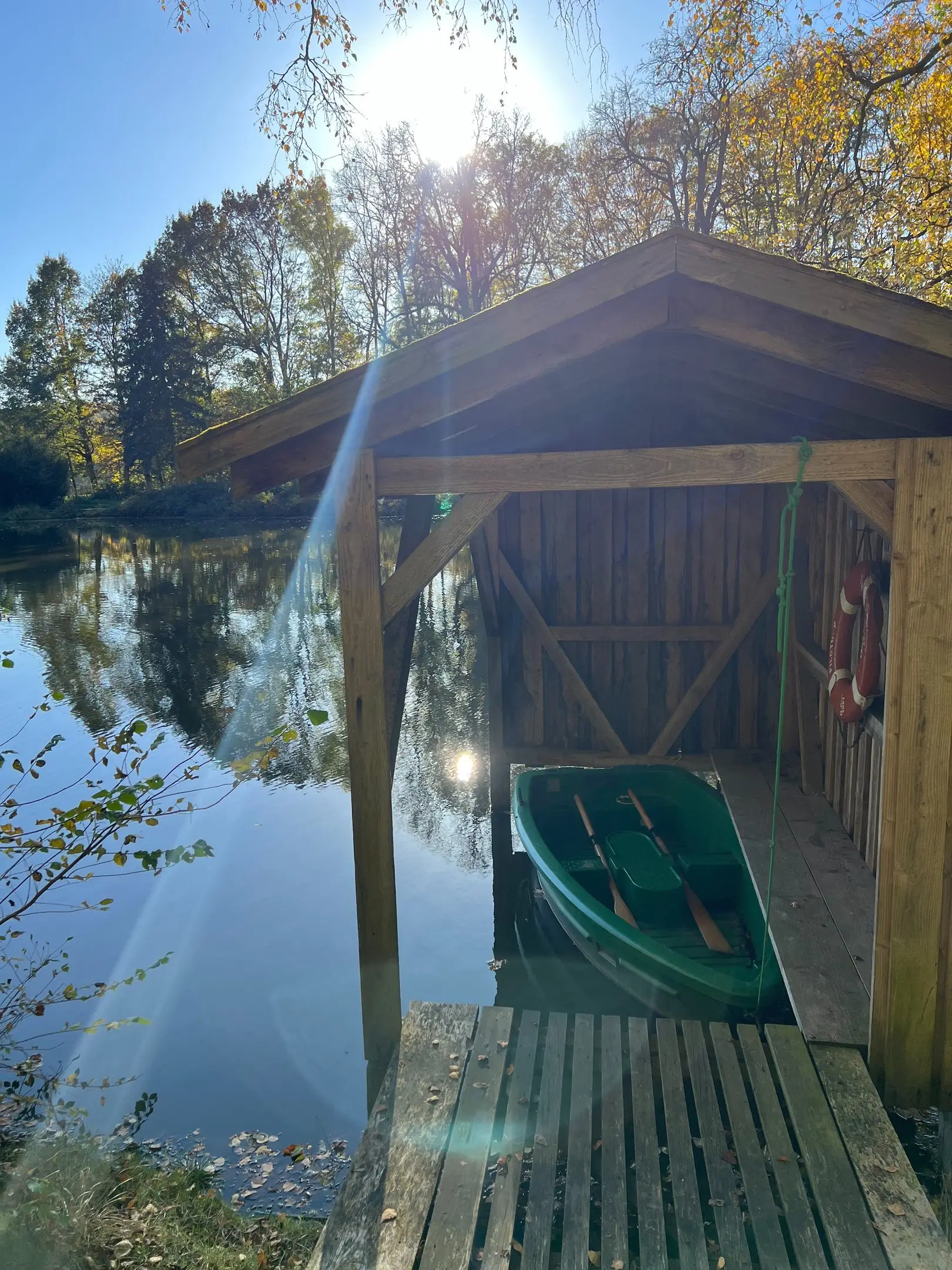 Bootshaus am See mit Ruderboot im Gegenlicht